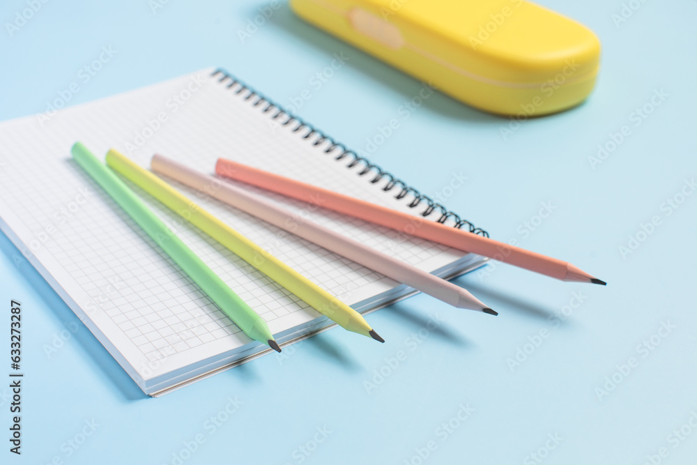 Multi-colored pencils lie on an open notebook, school supplies, back to school, preparation for school Multi-colored pencils lie on an open notebook, school supplies, back to school, preparation for school