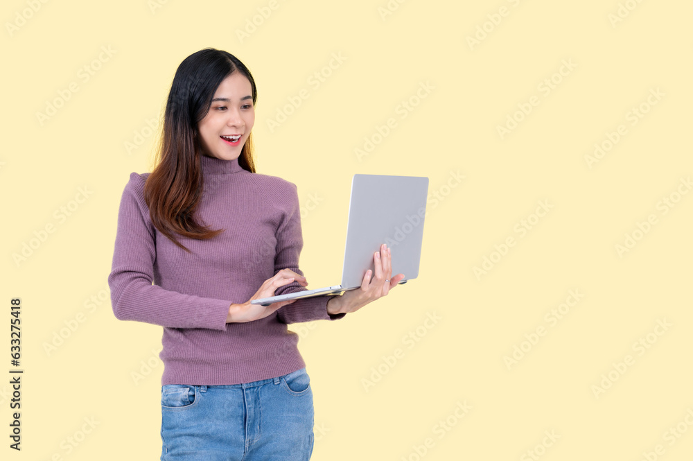 A beautiful Asian woman holding a laptop, looking at her laptop screen with a happy face A beautiful Asian woman holding a laptop, looking at her laptop screen with a happy face