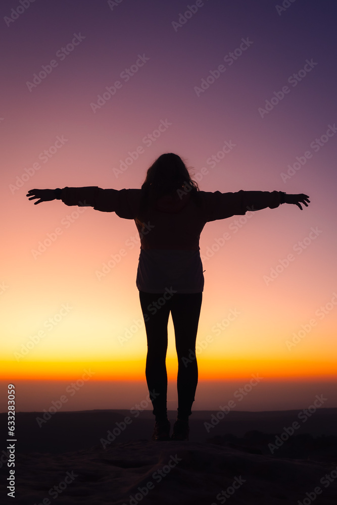 silhouette of a person in the sunset with arms outstretched