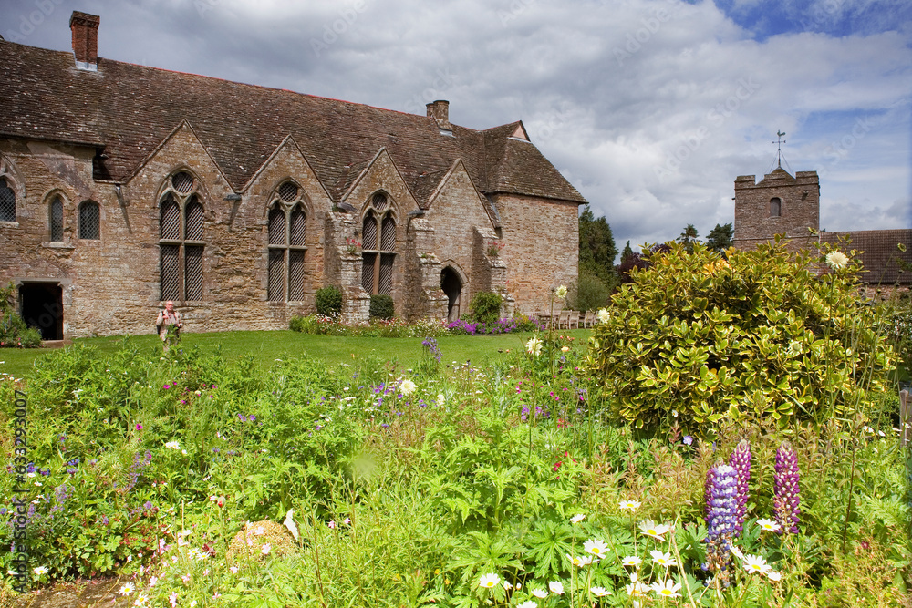The inner courtyard, 13th century Great Hall and churchtower of St. John the Baptist, seen from across the glorious flowerbeds, Stokesay Castle, Shropshire, UK