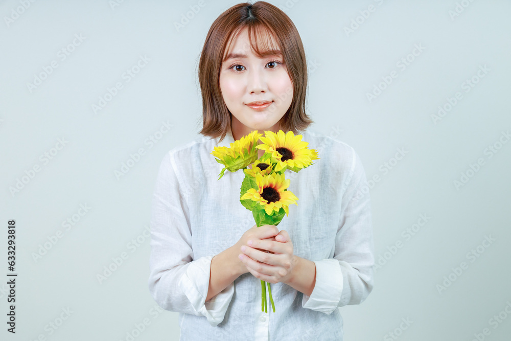 向日葵を持ったカメラ目線の若い女性 向日葵を持ったカメラ目線の若い女性