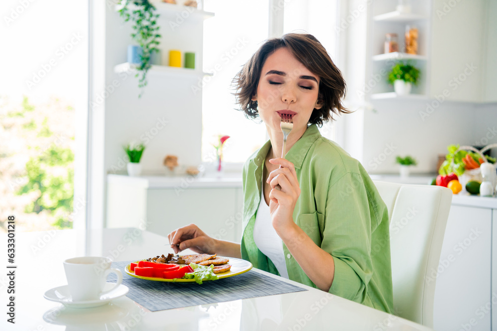 Photo of funky dreamy lady dressed green shirt enjoying tasty meal closed eyes indoors house kitchen Photo of funky dreamy lady dressed green shirt enjoying tasty meal closed eyes indoors house kitchen