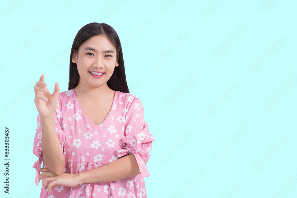 Young preetty Asian beautiful female with black long hair in pink shirt shows present something while isolated on light blue background. Young preetty Asian beautiful female with black long hair in pink shirt shows present something while isolated on light blue background.