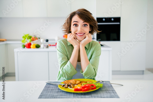 Photo of excited funky lady dressed green shirt waiting eating tasty supper indoors house kitchen photo