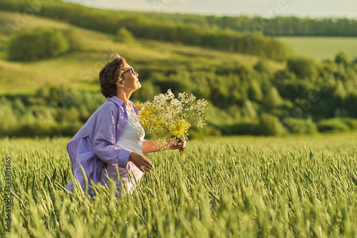 Elderly woman in stylish clothing relaxing in a lush meadow, embodying the fulfilling experiences offered in senior communities