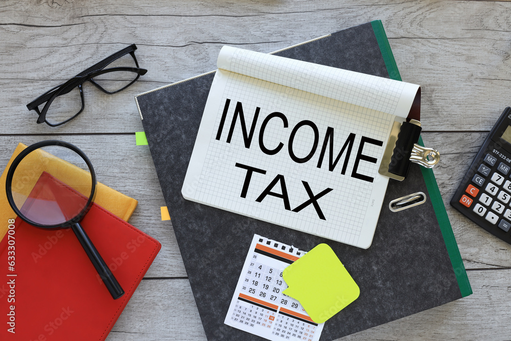 Income and Tax text on a notebook on a folder. red notepad. magnifying glass Income and Tax text on a notebook on a folder. red notepad. magnifying glass
