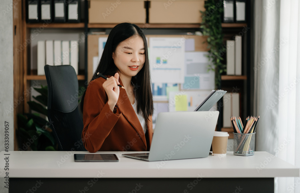 Asian businesswoman working in the office with working notepad, tablet and laptop documents in office. Asian businesswoman working in the office with working notepad, tablet and laptop documents in office.
