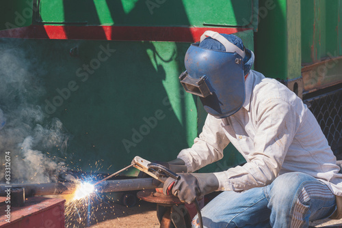 Welder with safety equipment using arc welding machine to welding galvanized steel pipe for improvement building structure in construction site area