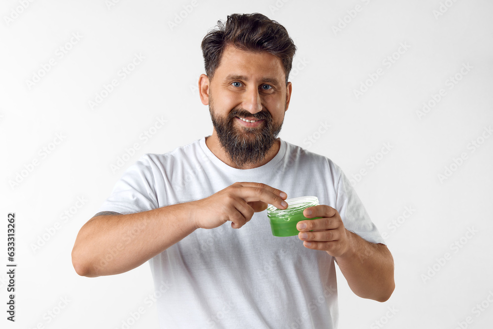 Handsome, bearded mature man taking care after skin with moisturizing face gel against white studio background. Concept of men's beauty, skin care, cosmetology, health and wellness. Copy space for ad Handsome, bearded mature man taking care after skin with moisturizing face gel against white studio background. Concept of men's beauty, skin care, cosmetology, health and wellness. Copy space for ad