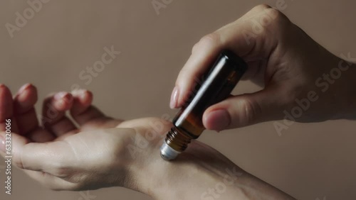 Woman applying natural rollerball aroma oil on her wrist close up photo