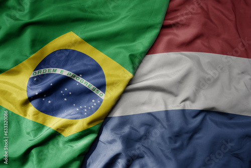 big waving realistic national colorful flag of brazil and national flag of netherlands .