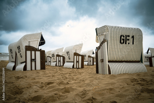 Fototapeta Naklejka Na Ścianę i Meble -  Roofed wicker beach chairs at the baltic sea beach, coast at the island of Usedom in Germany, storm and rain over the brackish water, high waves, storm warning