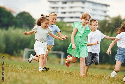 Running, active time spending. Kids are having fun on the field at daytime together