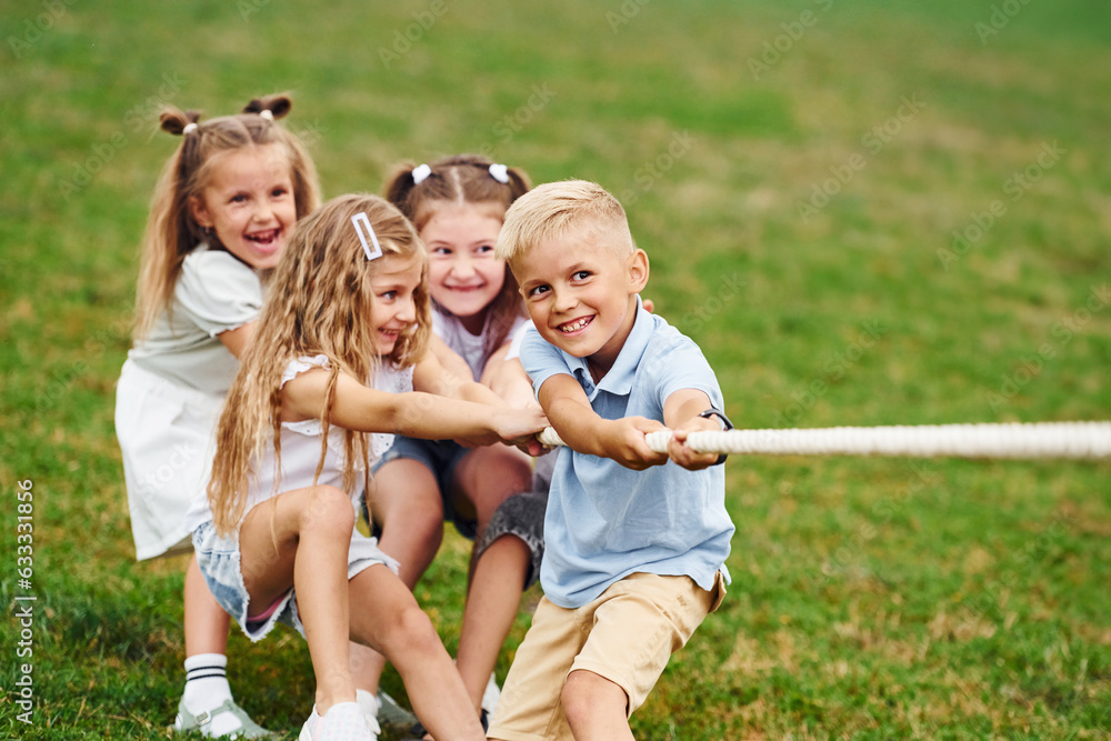 Fototapeta premium Struggle is real. Playing tug of war game. Kids are having fun on the field at daytime together