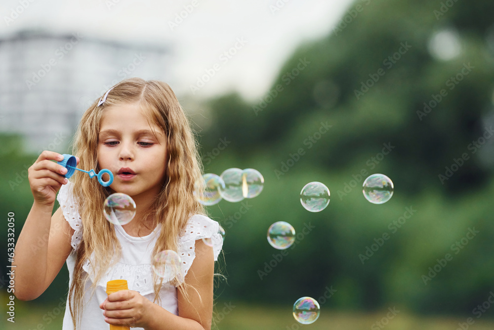 Portrait of little girl that is playing with bubbles outdoors