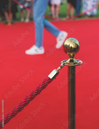 Red carpet with ropes and golden barriers on a luxury party entrance, cinema premiere film festival event award gala ceremony, wealthy rich guests arriving, outdoor decoration elements, summer day photo