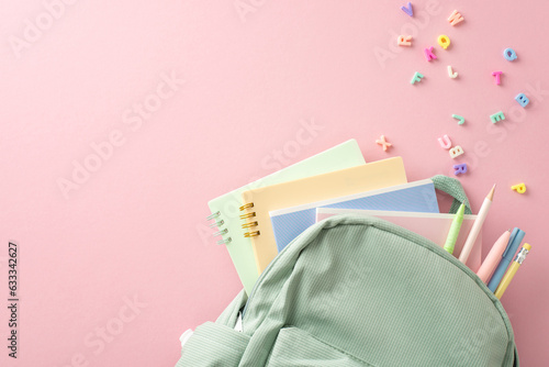 Schoolgirl\'s toolkit displayed from top view on pink background: sage backpack with pens, pencils, colorful copybooks, and alphabet letters. Great for promotions