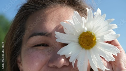 Happy woman with big chamomile in her hand in summer field. Carefree girl enjoys freedom and tranquility in the countryside during her vacation. The concept of rest or relaxation and happiness or photo