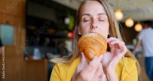 Young woman with bang eating croissants at cafe