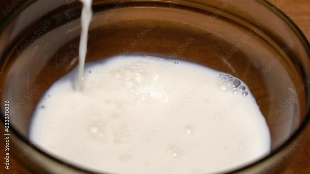 Fresh milk is poured into a bowl on a wooden table. Fresh milk is poured into a bowl on a wooden table.