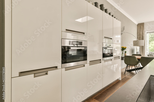 Quadro em tela a modern kitchen with white cabinetry and wood flooring in an open plan living r