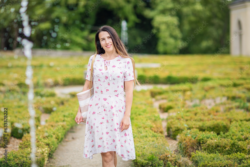 Lifestyle portrait of young pretty woman walking near fountain in a beautiful old park of a small French town Lifestyle portrait of young pretty woman walking near fountain in a beautiful old park of a small French town