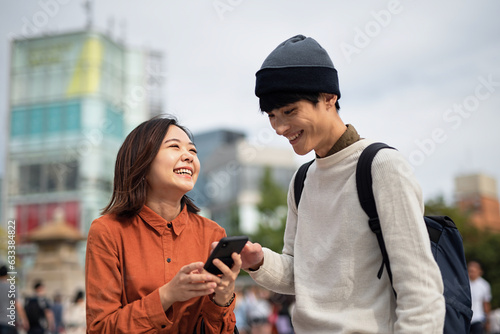 街中でスマートフォンを見ている笑顔のカップル