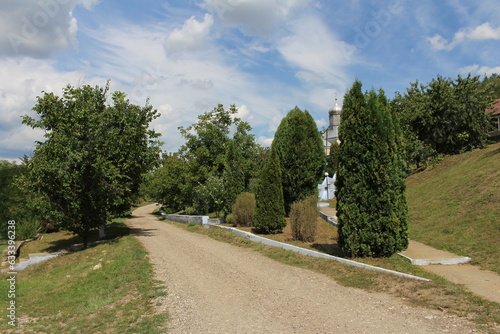 A dirt road with trees and a building in the background