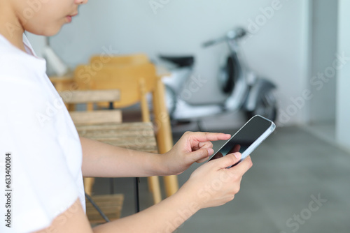 A woman sitting in a restaurant looks at the screen of her cell phone and reads a message. Woman hands with smartphone for online shopping and payment. Shopping service on online web. Spending money.