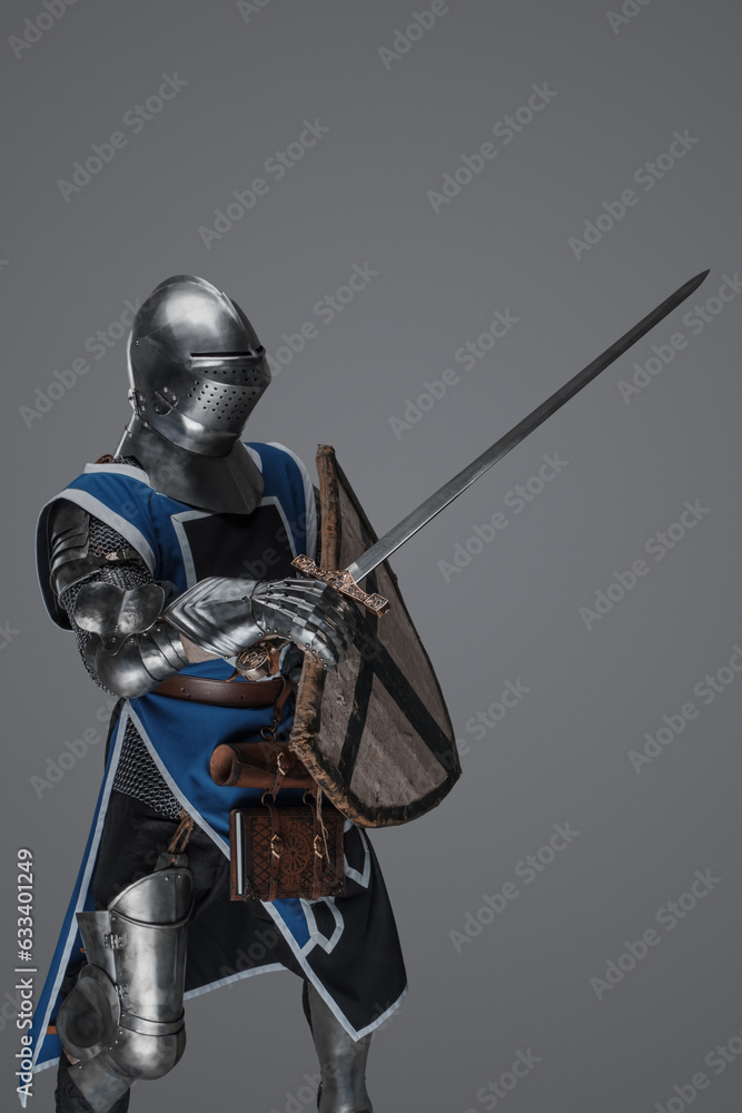 Naklejka premium Blue surcoat-wearing medieval knight actively swinging sword in battle on gray background