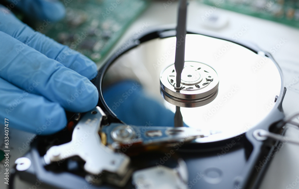 Male repairman wearing blue gloves dismantles specialized professional screwdriver hard drive. Performs fault diagnostics and performs urgent repairs recovery of lost data during deletion HDD closeup Male repairman wearing blue gloves dismantles specialized professional screwdriver hard drive. Performs fault diagnostics and performs urgent repairs recovery of lost data during deletion HDD closeup