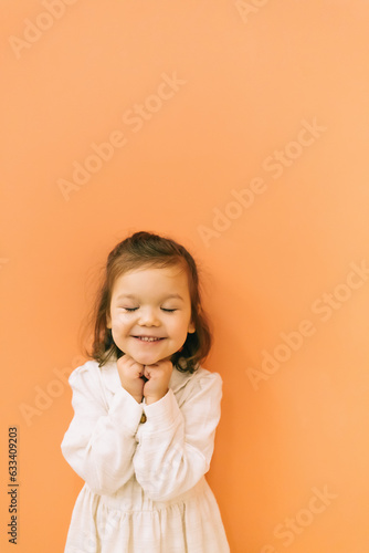 Smiling little girl near orange wall