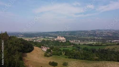 Aerial drone view of castle called Castello di Torrechiara between tree branches , Parma, Emilia-Romagna, Italy. Bird eye view of castle with medieval and renaissance architectural features on hill