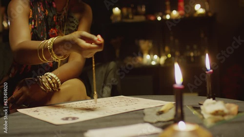 Cropped shot of seer swinging pendulum on chain over piece of paper with letters when predicting future