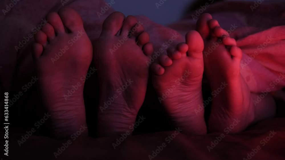Two pairs of female feet in bed. Foot fetish. LGBT relations. Two women in bed. Red light. Two pairs of female feet in bed. Foot fetish. LGBT relations. Two women in bed. Red light.