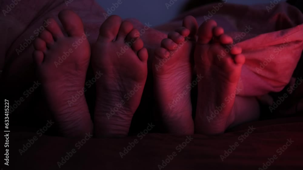 Two pairs of female feet in bed. Foot fetish. LGBT relations. Two women in bed. Red light. Two pairs of female feet in bed. Foot fetish. LGBT relations. Two women in bed. Red light.