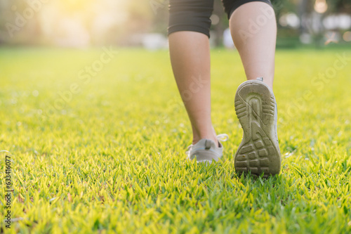 jogger woman. close up person training sport runner young female shoe on grasses in public park. fitness leg and foot exercise athlete. marathon in nature. active healthy lifestyle workout concept.