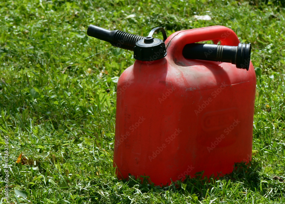 Red fuel canister with dispenser on the grass Red fuel canister with dispenser on the grass