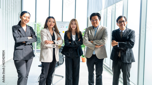 Asian male and female work team in suits standing with arms crossed arms crossed ready to serve and proud of work success business professional standing in company conference room