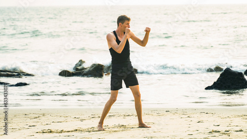 young man boxing on the coastline in a black sportswear