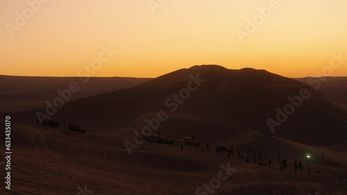 Puesta del sol en desierto, con montañas de arena en el fondo (desierto de hucachina perú) photo