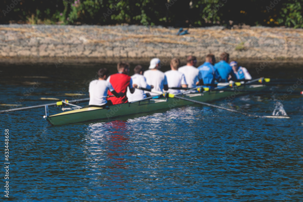 Naklejka premium Group of rowing team athletes sculling during competition, kayak boats race in a rowing canal, regatta in a summer sunny day, canoeing water sports team training in a river