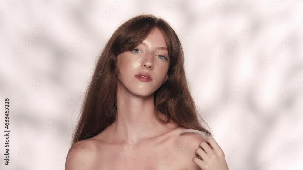 Beautiful brunette model with long hair and blue eyes playing with small feather Beautiful brunette model with long hair and blue eyes playing with small feather