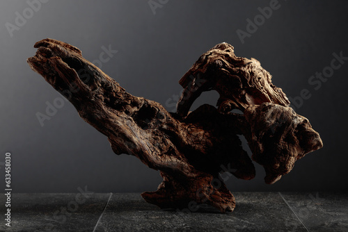 Old dry wooden snag on a black stone table.
