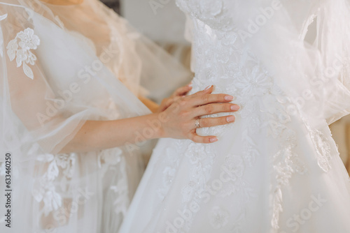 a beautiful girl with a wedding hairstyle in a transparent robe is preparing for a wedding in a hotel with a royal interior. The bride poses next to her wedding dress on a mannequin