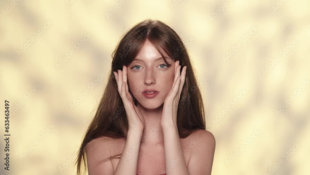 Attractive model with long hair touching her perfect skin on the face and looking at the camera Attractive model with long hair touching her perfect skin on the face and looking at the camera