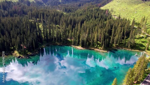 Idyllic nature scenery- trasparent mountain lake Carezza surrounded by Dolomites rocks- one of the most beautiful lakes of Alps. South Tyrol region. Italy, aerial drone video photo