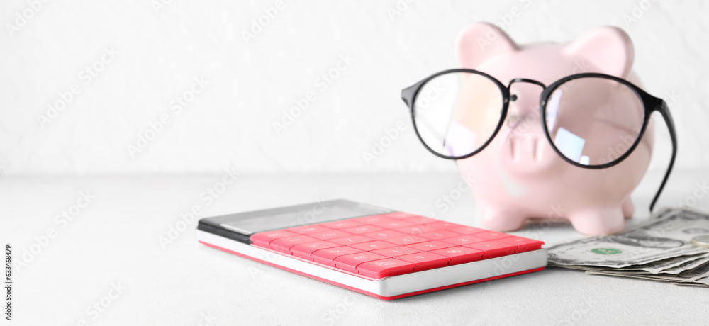 Piggy bank with eyeglasses, money and calculator on light background with space for text Piggy bank with eyeglasses, money and calculator on light background with space for text
