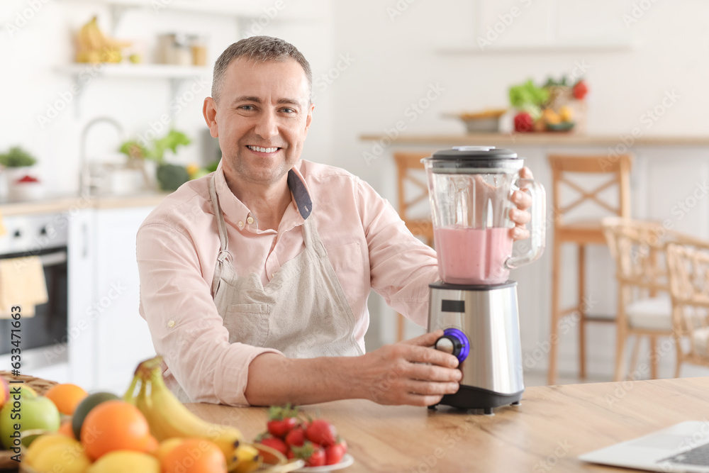 Mature man making fruit smoothie with blender in kitchen Mature man making fruit smoothie with blender in kitchen