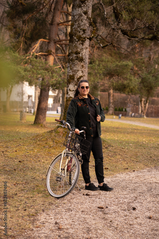 woman walking in a park taking her bycicle